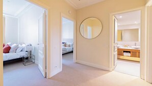 A hallway with a bed, a mirror, and a bathroom with a sink and towel rack. - JUST STEPS AWAY FROM THE MONNAIE MUSEUM, SEINE RIVER & PONT NEUF – SAINT GERMAIN (Paris)