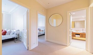 A hallway with a bed, a mirror, and a bathroom with a sink and towel rack. - JUST STEPS AWAY FROM THE MONNAIE MUSEUM, SEINE RIVER & PONT NEUF – SAINT GERMAIN (Paris)