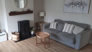Ein modernes Wohnzimmer mit grauem Sofa, einem Flachbildfernseher, einem Kamin, einem Holztisch und einer Wandregal mit Dekoration.