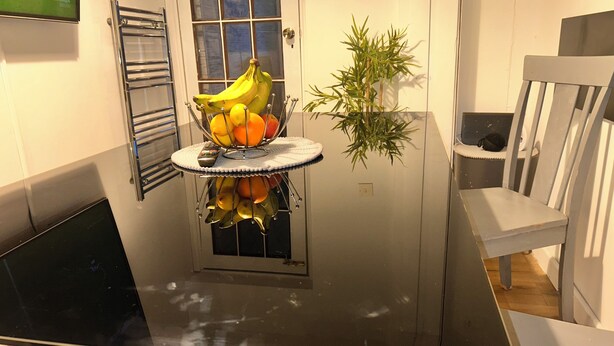 A small room with a window, a radiator, a chair, and a table with a fruit bowl. - Charming 4-bedroom House Rental in Basildon, UK (Basildon)