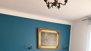 Ein modernes Wohnzimmer mit einer türkisfarbenen Akzentwand, einem grauen Sofa, einem Holztisch und einem Esstisch mit Kerzen.