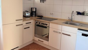 Eine moderne Küche mit weißen Schränken, einem eingebauten Backofen, einem Geschirrspüler und einem Fenster für natürliches Licht.