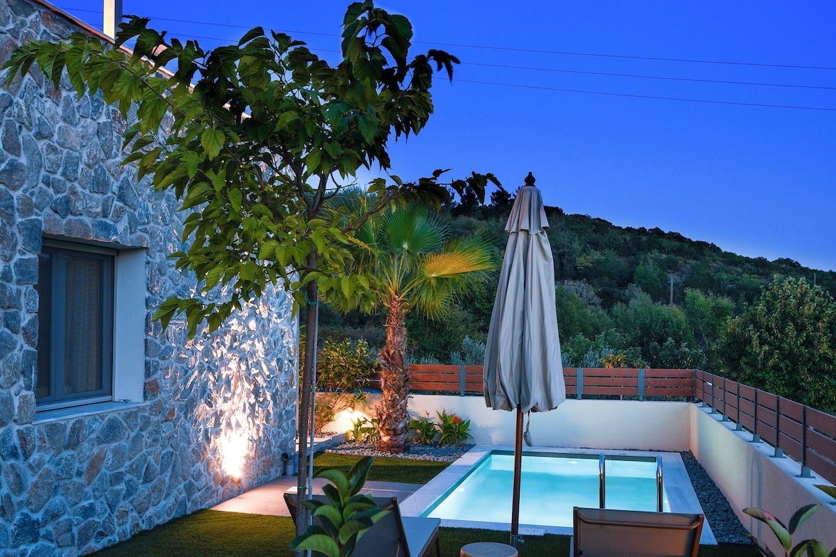 Una casa de piedra con piscina, mobiliario exterior y vistas a las colinas.