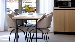 Una cocina moderna con una mesa de comedor, sillas, un frutero y un microondas.