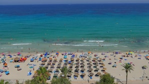 Ein Strand mit vielen Sonnenschirmen und Menschen.