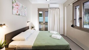 Ein Hotelzimmer mit Bett, Wand-Klimaanlage, Fenster mit Vorhängen und Deckenleuchte.