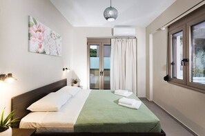 A hotel room with a bed, a wall-mounted air conditioner, a window with curtains, and a ceiling light fixture. - Family Villa w/ Private Pool & BBQ, near the beach (Rethymno)