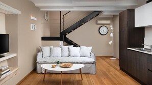 A modern living room with a sofa, coffee table, and a staircase leading to another level. - Dimore Apartment Monte (Rovinj)