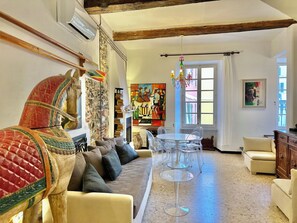 A living room with a sofa, a dining table with chairs, a wooden cabinet, and a horse sculpture. - UNIQUE HOUSE: on the main square, sea view, air conditioning, 2 bathrooms, SPA (Vernazza)