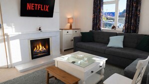 A living room with a fireplace, a sofa, a coffee table, and a TV displaying the Netflix logo.