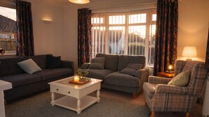 A cozy living room with a sofa, two armchairs, a coffee table, and a lamp.