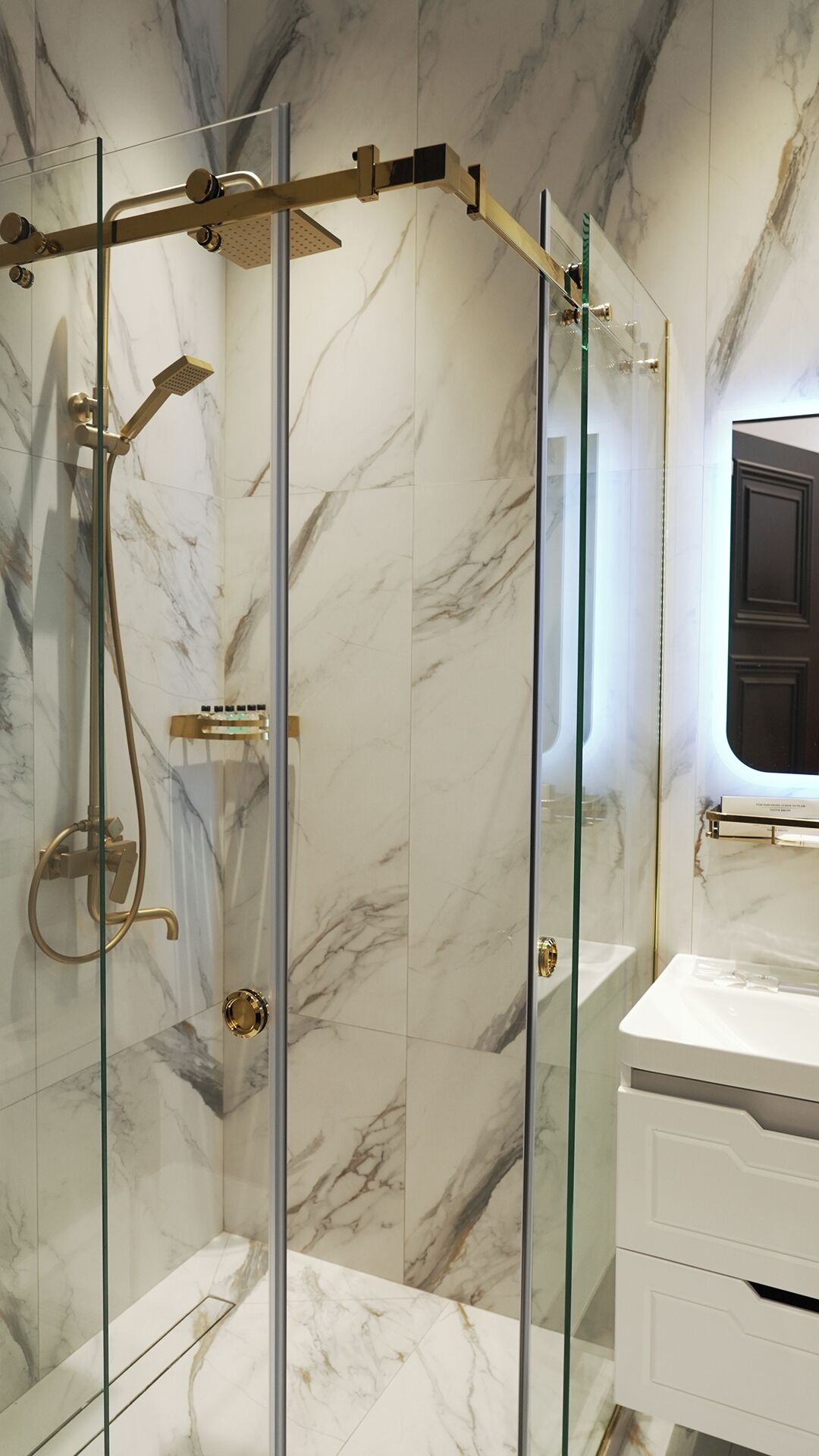 A modern bathroom with a glass-enclosed shower, marble walls, and a white vanity.
