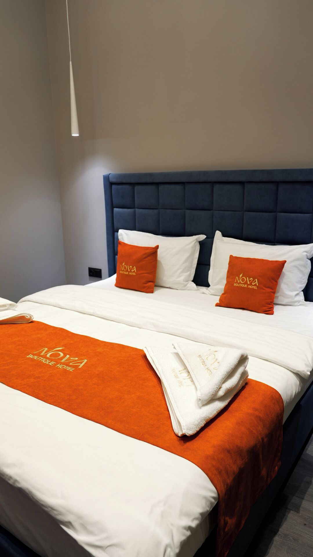 A hotel room with a bed, two pillows, a blanket, and a headboard.