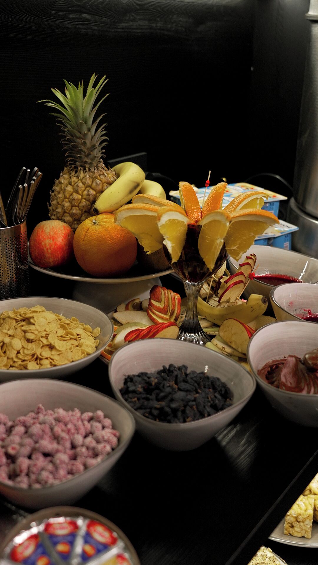 Uma mesa com diversos alimentos, incluindo frutas, cereais e outros petiscos.