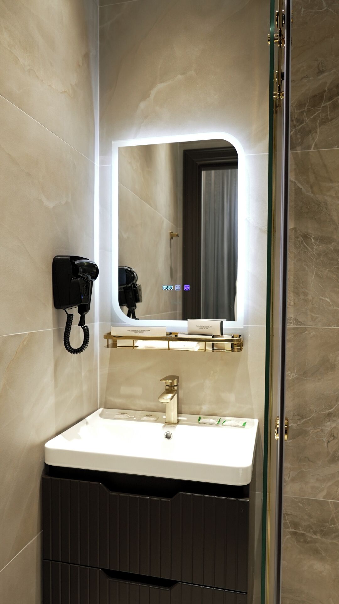 A modern bathroom with a built-in sink, a mirror, a hairdryer, and a telephone.