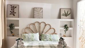 A neatly made bed with a leaf-patterned bedspread, a decorative headboard, and two bedside tables with potted plants. - Di Fiore Guesthouse (Naples)