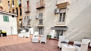 A courtyard with outdoor furniture, a tiled floor, and a building with multiple balconies. - Di Fiore Guesthouse (Naples)