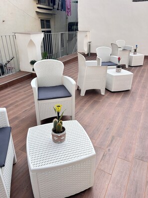 Eine Dachterrasse mit Korbmöbeln, einer Kakteenpflanze und einem Blumentopf.
