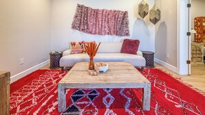Un salon comprenant un canapé, deux tables d’appoint, une table basse et un tapis rouge à motifs.