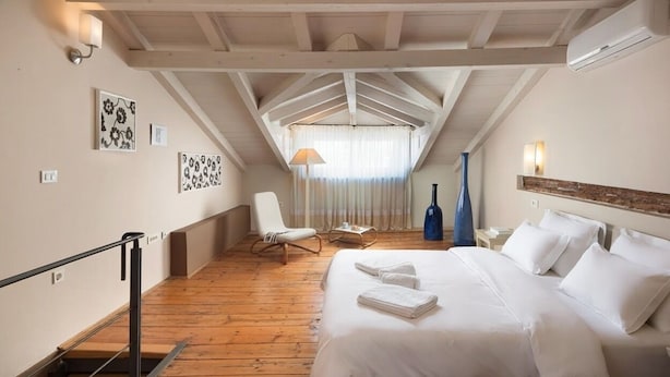 A bedroom with a wooden floor, a bed with white linens, a chair, a lamp, and artwork on the walls. - Dimore Holiday Home Silva (Rovinj)