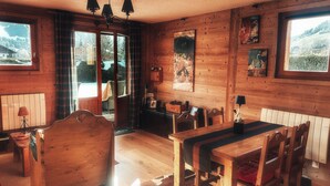 Un intérieur en bois comprenant une table à manger, des chaises, un canapé et une cheminée.