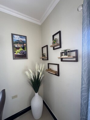 Ein Flur mit einer weißen Vase, gerahmten Kunstwerken und Regalen an der Wand.