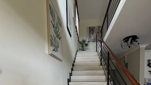 Eine Treppe mit Holzgeländer, weißen Wänden und gerahmten Kunstwerken.
