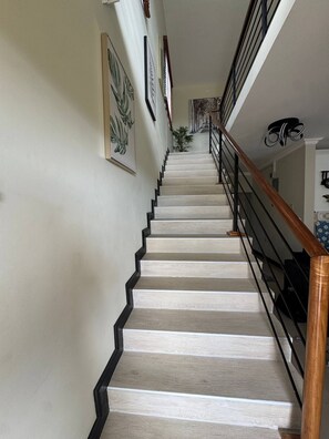 A staircase with a wooden handrail, white walls, and framed artwork. - Jahiem's Paradise (Ocho Rios)