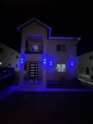 A two-story house with a balcony on the upper floor, illuminated by blue lights. - Jahiem's Paradise (Ocho Rios)