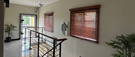 A polished interior with a staircase, potted plants, and wooden blinds.