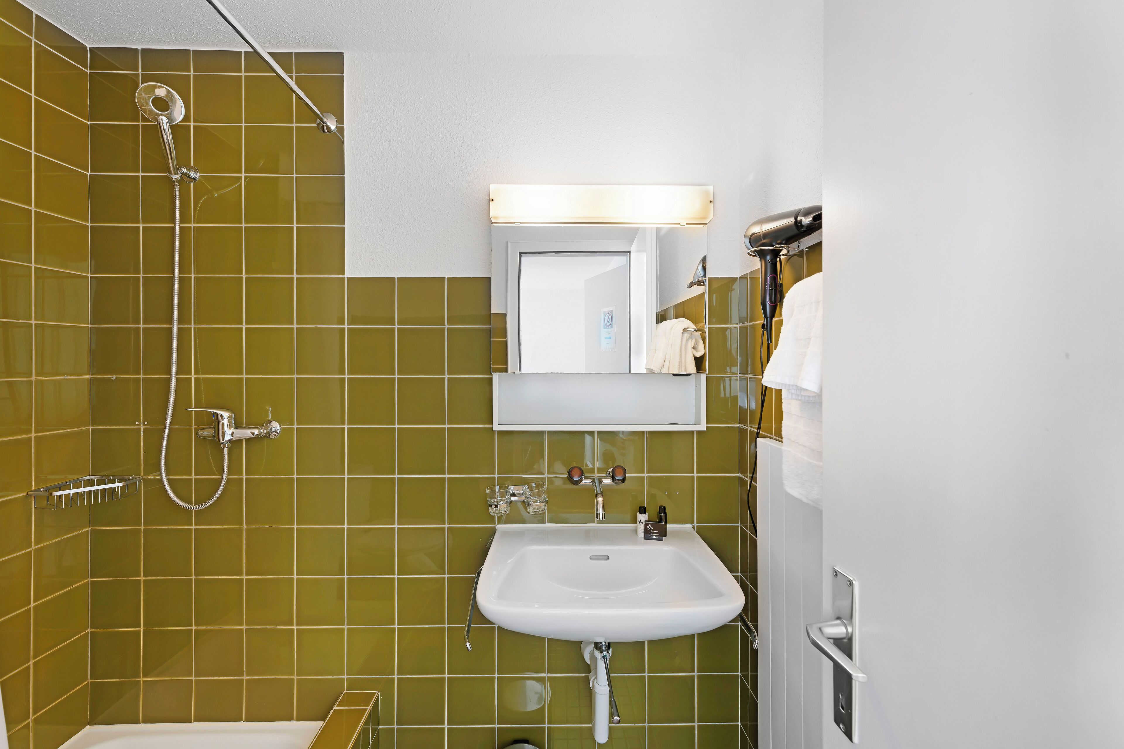 Un baño con ducha, lavamanos y espejo.