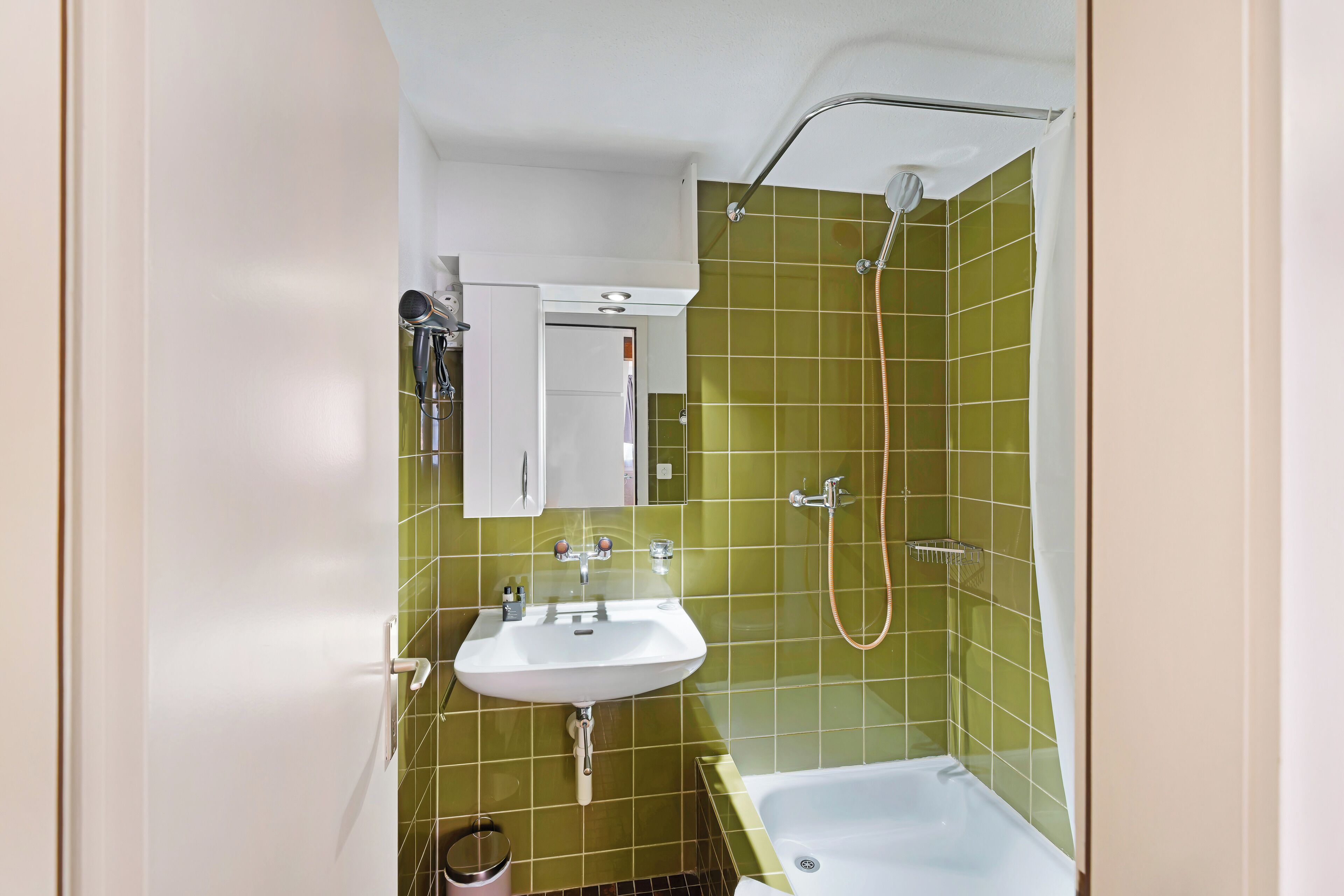 Ein Badezimmer mit Waschbecken, Spiegel und Dusche.