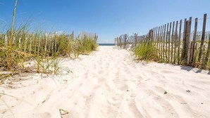 A sandy beach path with wooden fences on either side. - Shoreline Towers (Gulf Shores)