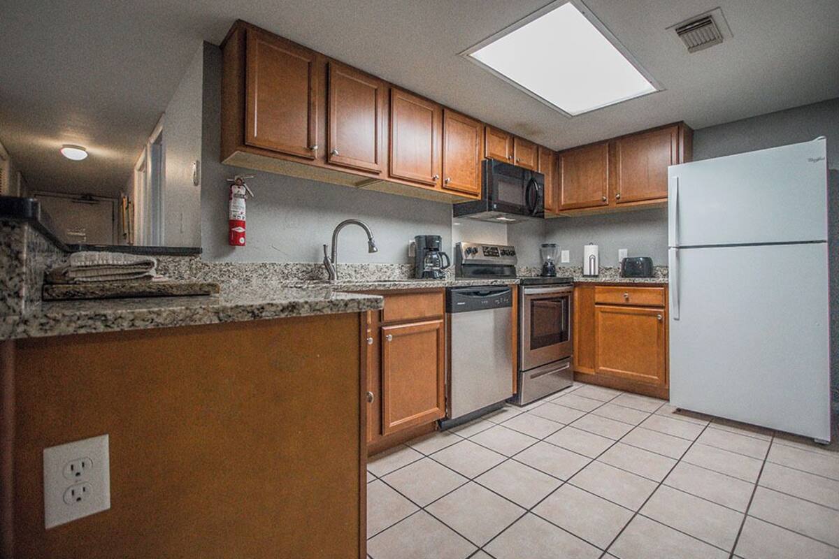 A kitchen with wooden cabinets, a white refrigerator, a microwave, a stove, and a dishwasher.