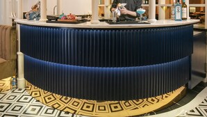 Un espace bar avec un comptoir, des étagères remplies de bouteilles et un sol à motifs.
