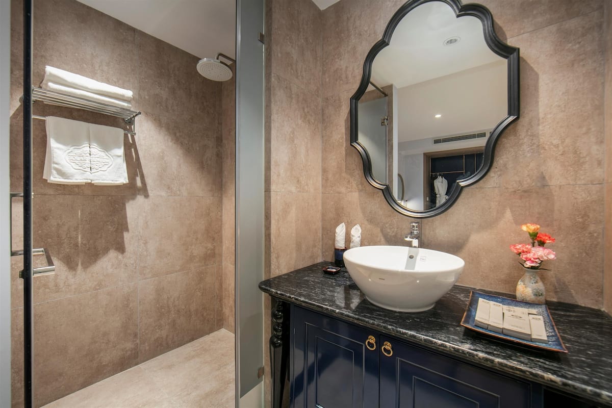 A bathroom with a large mirror, a white sink, and a vanity with dark cabinets.