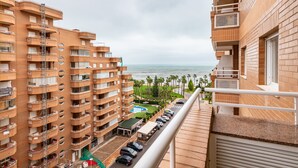 A high-rise building with multiple balconies, a parking area, and a view of the sea. - Seafront Apartment 'Vistamar' with Sea Views, Wi-Fi & Air Conditioning (Oropesa)