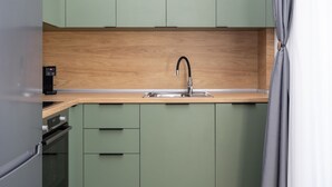Una cocina con encimera de madera, pileta de acero inoxidable y armarios verdes.