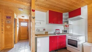 Une cuisine avec des murs en bois, un évier, une cuisinière et des placards rouges.