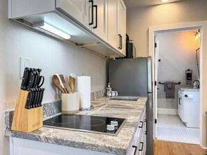Una cocina moderna con estufa integrada, un bloque de cuchillos y utensilios de madera.