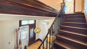 A staircase with dark steps and a wooden handrail, leading to a landing with a door and a window. - The Claret Cup Suite at The Hesch - Premier Location- Railyard Arts District (Santa Fe)
