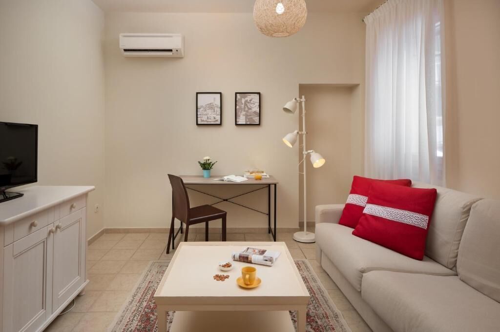A modern living room with a sofa, coffee table, TV, and a dining area with a table and chairs.