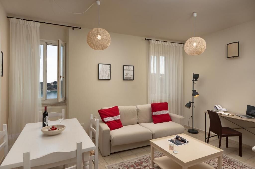A modern living room with a sofa, dining table, and a desk with a computer.
