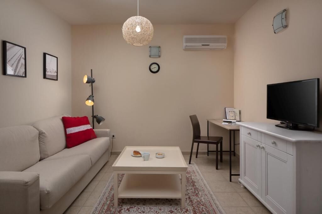 A compact living space with a sofa, a coffee table, a TV, a desk, and a chair.