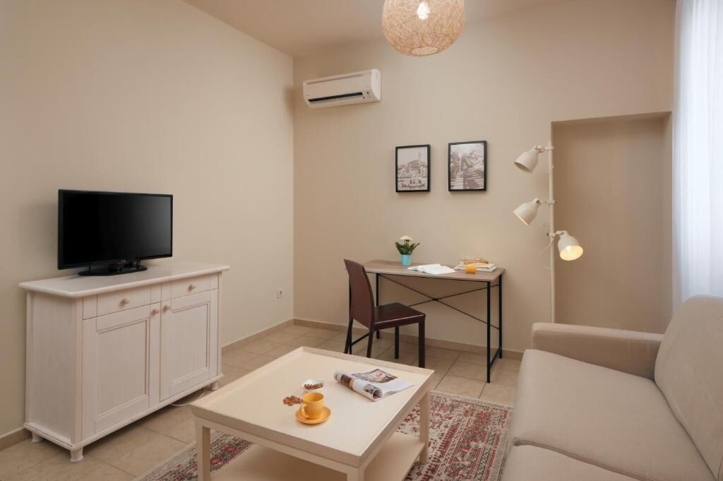 Sala de estar con televisor, mueble blanco, mesa de comedor y sofá.