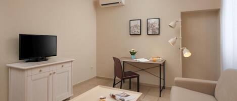 Sala de estar con televisor, mueble blanco, mesa de comedor y sofá.