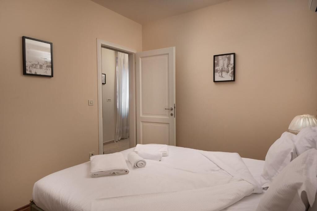 Una habitación de hotel con una cama, una puerta y dos cuadros en las paredes.