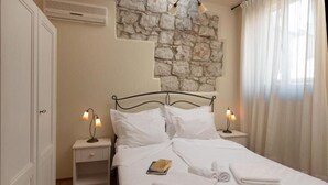 Ein Doppelbett mit weißen Bettwäsche, zwei Nachttischlampen, ein Buch und aufgerollte Handtücher.