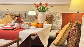 Ein Frühstückstisch für zwei Personen, gedeckt mit Tellern, Tassen und einer Vase mit Tulpen, inklusive einer Lampe.