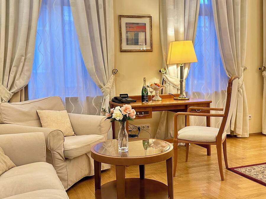 A well-furnished living room with a sofa, armchair, coffee table, and a desk with a lamp.